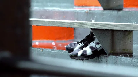 Rain falling  on athletic shoes in bleachers in slow motion Stock Footage 48669593
