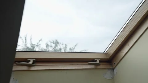 Rain falling on attic skylight window seen from interior during daytime with Stock Footage 314269722