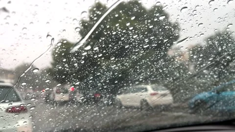 Rain falling on car windshield view. Inside a car at heavy rain storm. Video stock 221036786