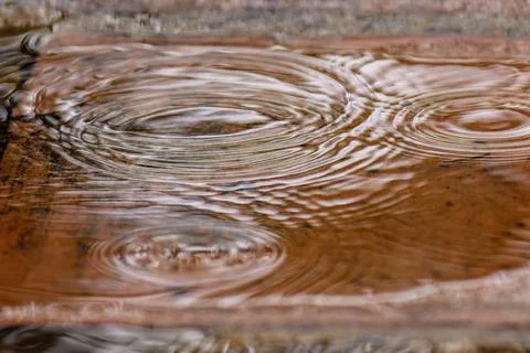 Rain falling on a clay tile floor forming puddles on it, close-up view captur Stock Photos