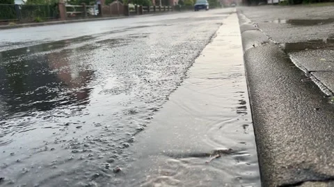 Rain falling on flooded street beside curb Stock Footage 344798829
