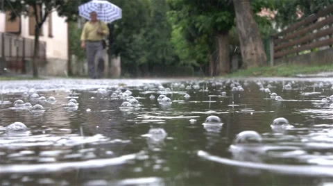 Rain falling in the foreground. Man with umbrella walking down the street, 4k. 스톡 동영상 53747595