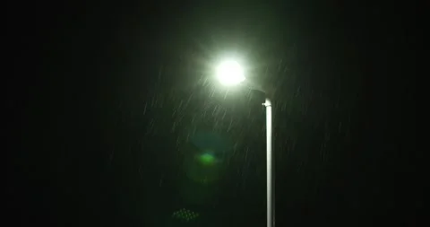 Rain falling in front of streetlight at night green bokeh Stock Footage 277387610