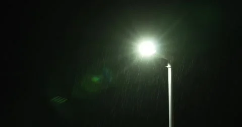 Rain falling in front of streetlight at night green bokeh steady Stock Footage 277387656