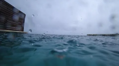 Rain falling on infinity pool overlooking ocean Stock Photos