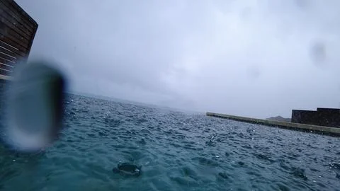 Rain falling on infinity pool by the sea during a stormy day Stock Photos