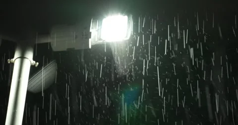 Rain falling at night in front of light Stock Footage 277387655