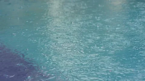 Rain falling into the pool filmed in slow motionWater surface with falling dr Stock Footage 169322341