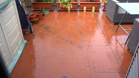 Rain falling on red brick terrace floor with blue flip flops and garden fur.. Stock Footage 337171519