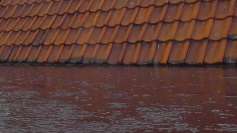 Rain falling on a rooftop in Holland, Netherlands, Europe. Red roof tiles in Stock Footage 79566852