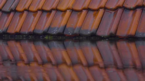 Rain falling on a rooftop in slow motion, red roof tiles in the background Stock Footage 79566912