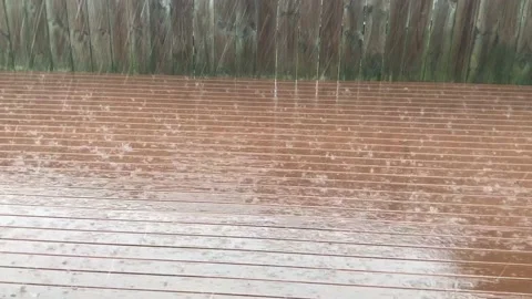 Rain falling on rust stained deck against wooden fence during a winter day Stock Footage 135271303