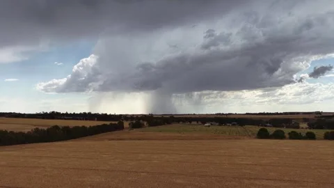 Rain falling from storm clouds over dry farmland Stock Footage 327945858