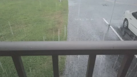 Rain falling view from over balcony edge. Green plants and water. Pan up Stock Footage 242267775