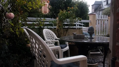 Rain falling on wet table and chairs at french patio Stock Footage 119030529