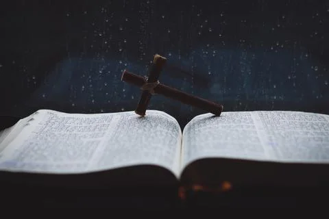 Rain falling on the window and flowing raindrops, cross and bible Stock Photos