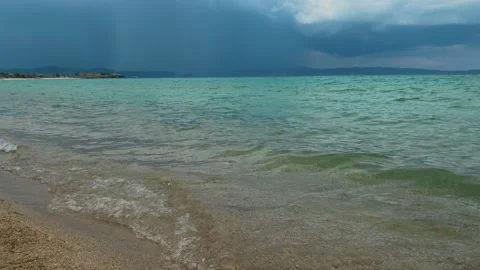 Rain falls from dark clouds above turquoise sea. Trani Ammouda, Greece Stock Footage 339619597