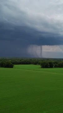 Rain falls from the dark clouds above the grassland Stock Photos