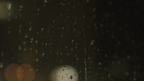 Rain falls down a glass window at night Stock Footage 241494883