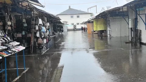 Rain falls on empty market in city during afternoon hours with shops and puddles Stock Footage 336250275