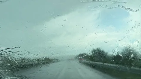 Rain falls on the highway while a car travels with windshield wipers in motion Stock Footage 337942746