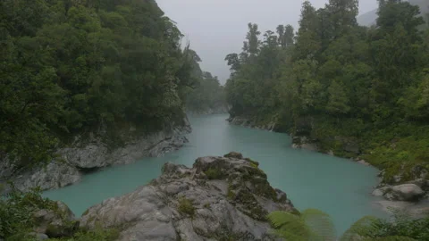 Rain falls over a blue-colored river branch, in New Zealand Stock Footage 219898197