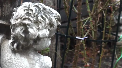 Rain that falls over a concrete statue and plants in the garden Stock Footage 64309475