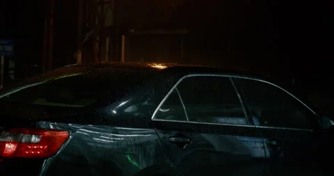 Rain falls on a parked car, it rains and drops of water drip onto the roof of Stock Footage 168256583
