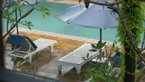 Rain falls on sun bed next to swimming pool at luxury hotel Bali Indonesia Stock Footage 84172879