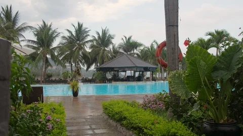 Rain falls on sun bed next to swimming pool at luxury hotel Stock Footage 92112118