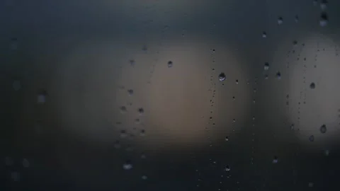Rain falls on a window, creating drops and streaks during a cloudy day Video stock 327990893