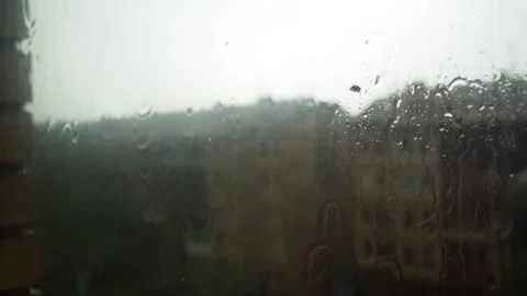 Rain falls on window glass covered with a mosquito net. Peering through, the Stock Footage 335567798