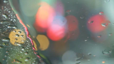 Rain falls on windshield with city lights in background 스톡 동영상 79529833