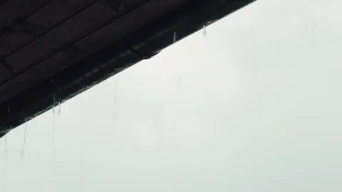Rain flows down from the roofing in the evening. Raindrops flow down, close-up. Vidéo 86115099