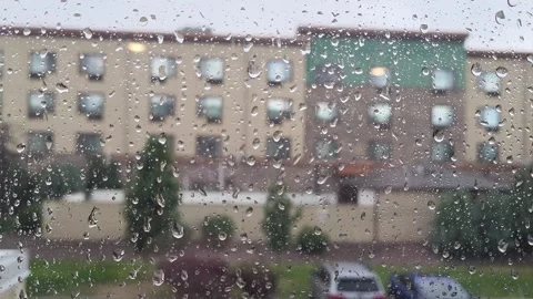 Rain forms rivulets down the window, blurring the distant building 库存影片 340237789