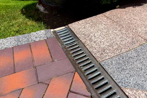 Rain grate to the joints of two paths of granite and paving slabs. Stock Photos