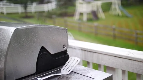 Rain hitting grill in slow motion with smoke swirling grilling outdoor in storm Stock Footage 205956818