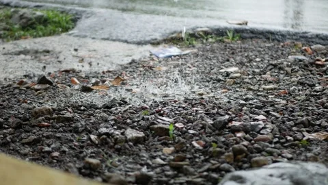 Rain hitting ground with vehicle passing by Stock Footage 258278712