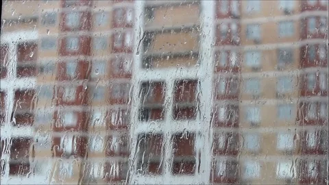Rain knocks on the eaves in the city, drops of water flow in surface the window. Stock Footage 77364007
