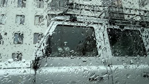A rain-lashed window obscures the background, showing a blurred, watery view of Stock Photos