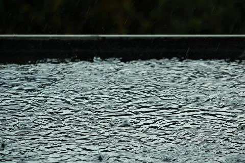 Rain is makes circles on a black flat roof Stock Photos