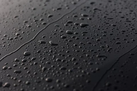Rain or water drops different size on a black shiny car hood surface. Water d Stock Photos