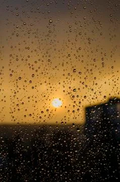 Rain outside window on background of sunset. Rain drops on glass during rain. Stock Photos