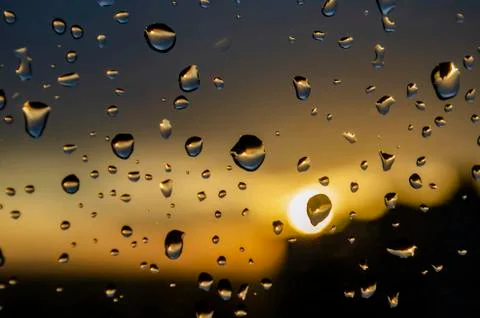 Rain outside window on background of sunset. Rain drops on glass during rain. Stock Photos