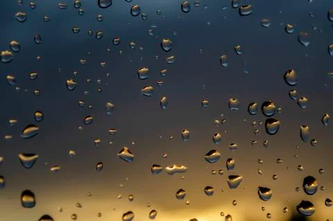 Rain outside window on background of sunset. Rain drops on glass during rain. Stock Photos