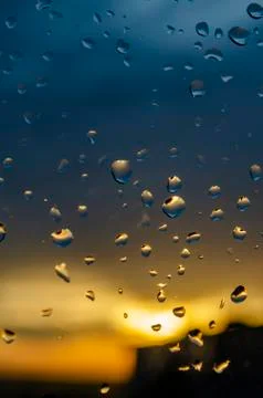 Rain outside window on background of sunset. Rain drops on glass during rain. Stock Photos