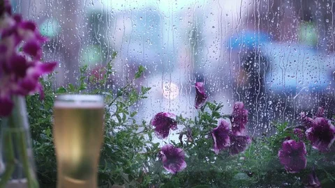 Rain outside the window of the café. A glass of beer. Raindrops on window glass Stockbeeldmateriaal 78547547