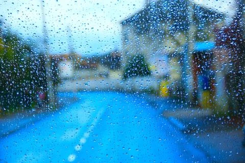 Rain outside window on city background. Water drops on glass during raining Stock Photos
