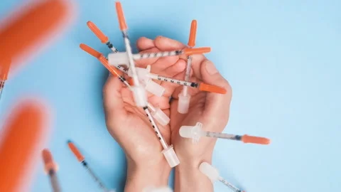 Rain of plastic insulin syringes falling into female hands on blue background Video stock 221152465