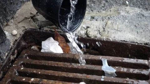 Rain pouring out of gutter down pipe into drain, slow motion Stock Footage 75743396